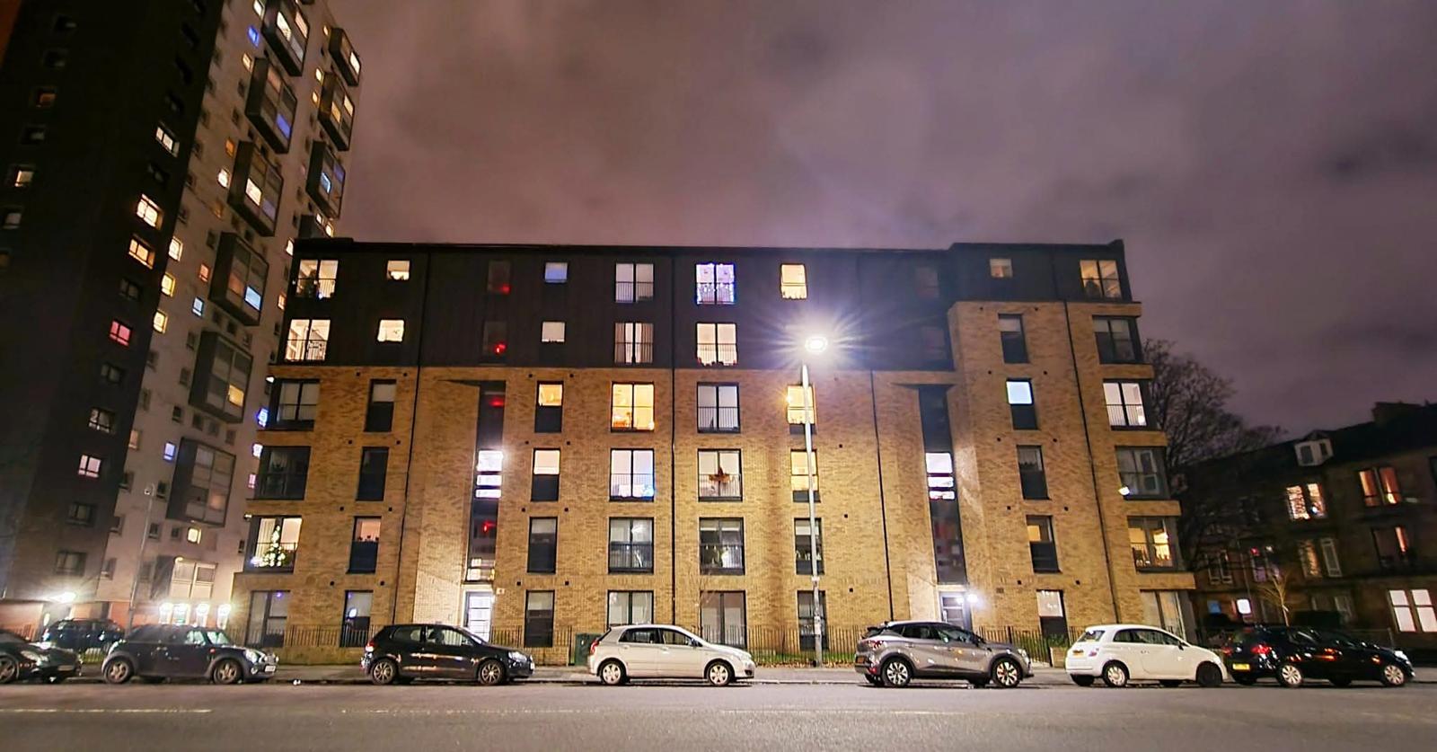 A modern residential apartment building in Glasgow at night