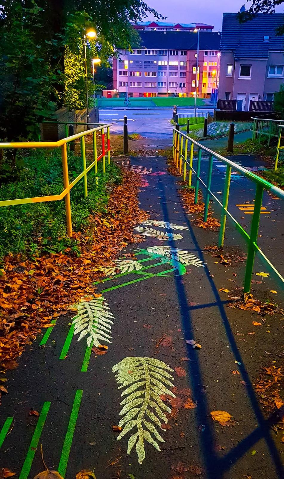 A colourful leaf-painted community path through a Glasgow neighbourhood