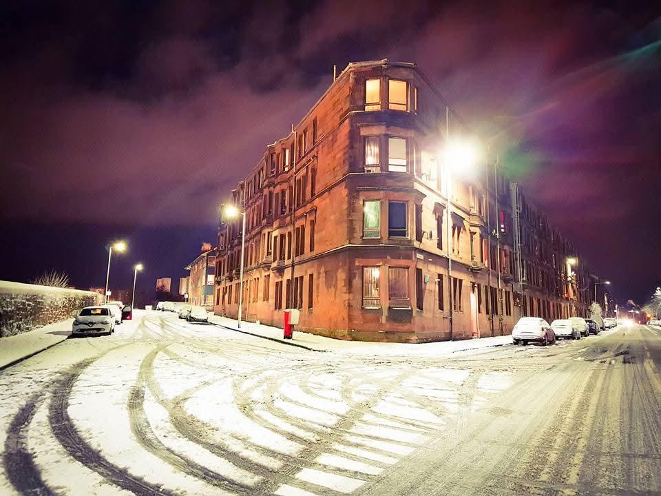 A Glasgow tenement street lit warmly at night